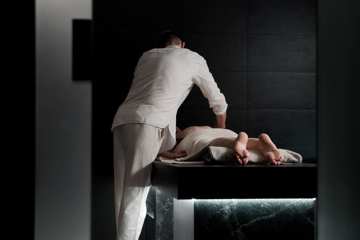 Therapist giving a massage in a calm, dimly lit treatment room